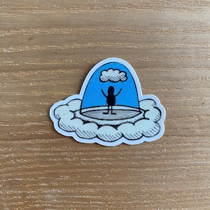 Op de afbeelding: Een zwart stokfiguur staat op een platform in een blauwe koepel met een witte wolk erboven. De koepel is omgeven door een witte wolk met zwarte contouren.