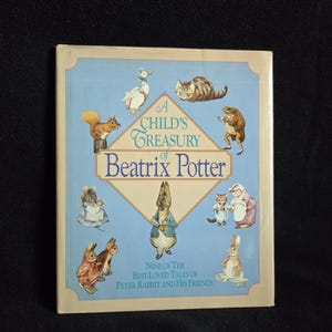May include: A Child's Treasury of Beatrix Potter book. The cover features illustrations of Peter Rabbit and other characters from the stories. The book is light blue with a cream-colored border and text that reads "Nine of the Best-Loved Tales of Peter Rabbit and His Friends."