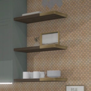 May include: Two dark brown wooden shelves with gold metal brackets mounted on a wall with a patterned tile design. The shelves are empty except for a white picture frame on the top shelf.