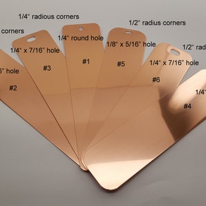 May include: Six copper-colored metal tags with different hole shapes and sizes. The tags are labeled with numbers 1 through 6 and have different corner radius measurements. The tags are arranged in a fan shape.