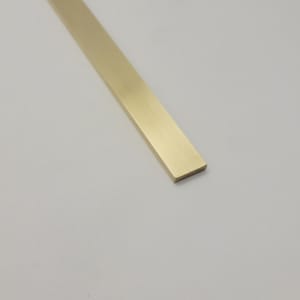 May include: A rectangular, solid brass bar with a polished finish. The bar is a warm gold colour and is positioned diagonally against a white background. The bar's edges are clean and sharp.