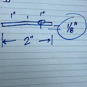 May include: A hand-drawn diagram on lined paper, featuring blue ink measurements. The diagram includes a 2-inch line, a 1-inch line, and a 1/8-inch measurement. Additional 1-inch measurements are also present.