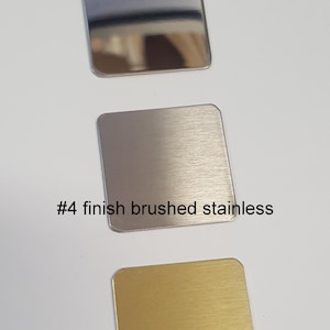 May include: Three metal samples, showing different finishes. The top sample is a polished stainless steel finish. The middle sample is a brushed stainless steel finish, labeled "#4 finish brushed stainless". The bottom sample is a gold finish.