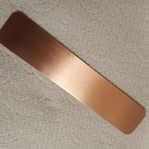 May include: A long, rectangular piece of brushed copper metal.