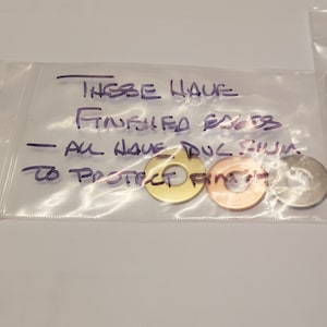 May include: Three metal washers with a protective film on them. The washers are gold, copper, and silver. The text on the bag reads "These have finished edges - all have dul film to protect finish."