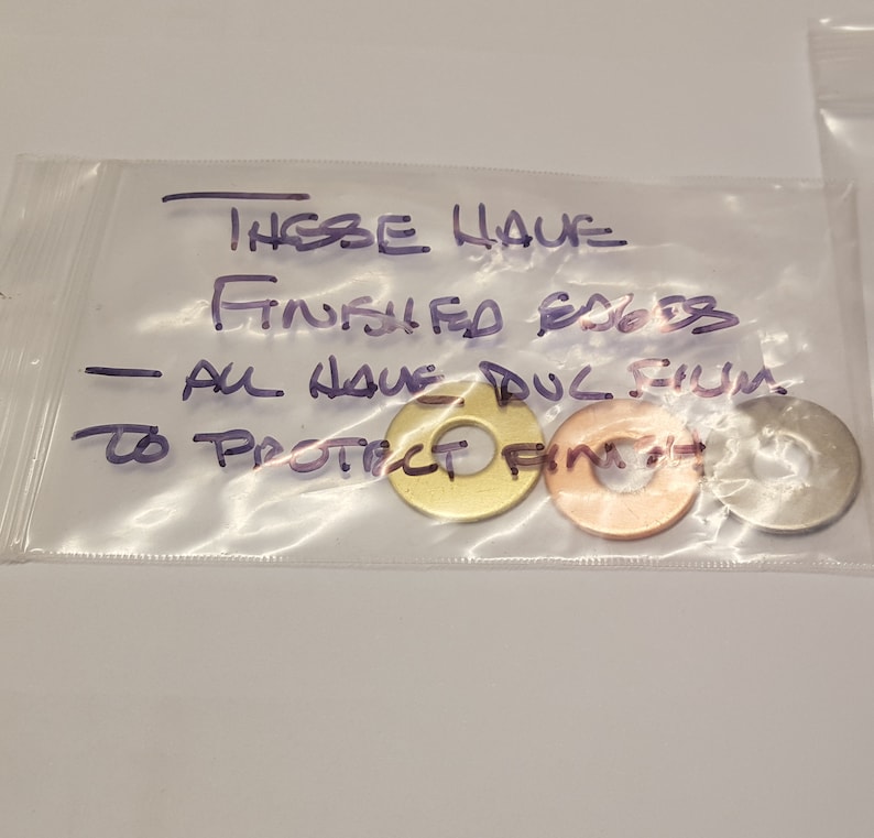 May include: Three metal washers with a protective film on them. The washers are gold, copper, and silver. The text on the bag reads "These have finished edges - all have dul film to protect finish."
