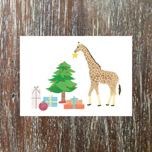 giraffe vakantie wenskaart met een stralende ster bovenop de kerstboom, cadeautjes en een giraffe met een kerstmuts