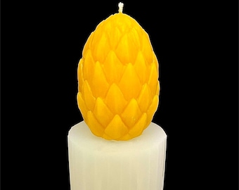 May include: A yellow candle shaped like a pineapple with a white base. The candle is on a black background.