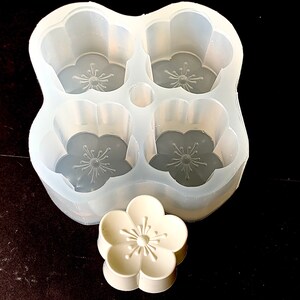 May include: A clear silicone mold with four flower-shaped cavities and a single flower-shaped silicone mold. The mold is designed for making soap, resin, or other crafts.