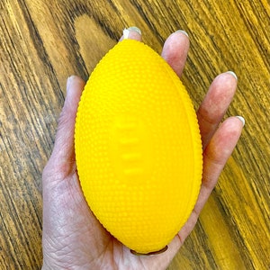 K&ouml;nnte beinhalten: Ein leuchtend gelber Gummifu&szlig;ball mit strukturierter Oberfl&auml;che.