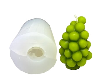 May include: A white silicone mold for making a grape candle. The mold is shaped like a bunch of grapes and has a hole in the bottom for pouring wax. A green grape candle is shown next to the mold.