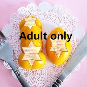 May include: Two yellow, star-shaped candies on a white doily with the text "Adult only" in black letters.