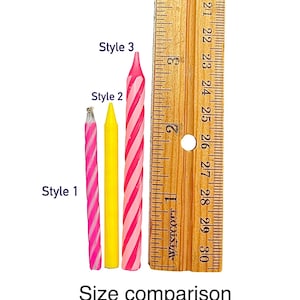 以下が含まれることがあります： 「スタイル1」、「スタイル2」、「スタイル3」とラベル付けされた、3つの異なるサイズの誕生日ろうそく。ろうそくはピンクと白のストライプ、黄色、ピンクと白のストライプです。サイズ比較のために定規が表示されています。