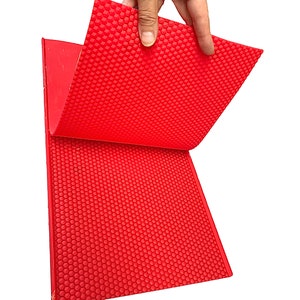 May include: Red silicone baking mat with a honeycomb pattern. The mat is flexible and can be used for a variety of baking purposes.