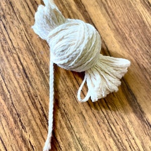 May include: A ball of natural white cotton twine, tied in a knot, with a long strand of twine extending from the knot.