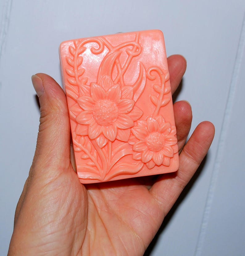 May include: A peach-colored soap bar with a floral design featuring sunflowers and leaves.