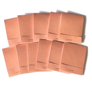 May include: A stack of ten blank, peach-colored notepads with a single staple in the center of each.