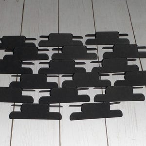 May include: A collection of black paper cutouts shaped like clouds. The cutouts are arranged in a staggered pattern, creating a layered effect.