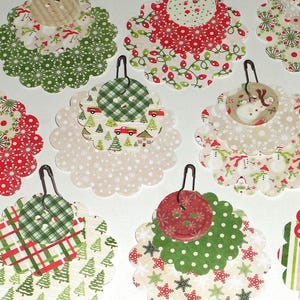 May include: A collection of festive Christmas ornaments with scalloped edges. Each ornament features a unique combination of patterned fabrics in red, green, and white, with metal hangers for display. Designs include polka dots, plaid, and holiday motifs.