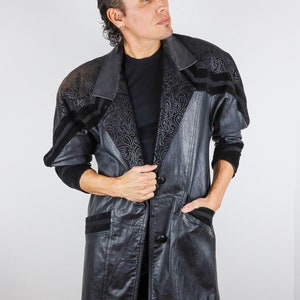 May include: A long black leather jacket with a paisley pattern on the collar and cuffs. The jacket has a single button closure and two pockets.