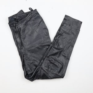 Könnte beinhalten: Schwarze Lederhose mit Reißverschluss und Knopfverschluss. Die Hose hat eine gerade Bein und ist aus weichem, geschmeidigem Leder gefertigt.