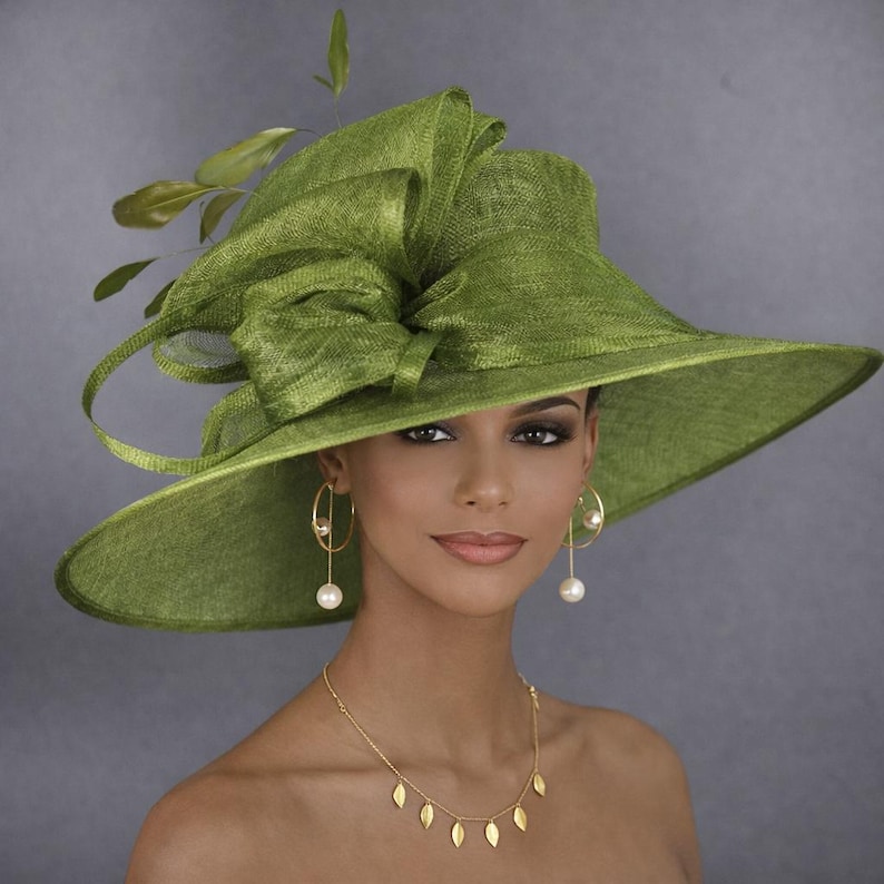 May include: A wide-brimmed olive green hat featuring a textured weave, a large decorative bow on the side, and green leaf accents. The hat is paired with gold drop earrings featuring white pearls and a gold necklace with small leaf-shaped charms.