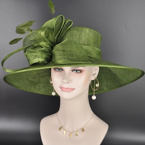 May include: An olive green wide-brimmed hat featuring a structured crown and a large, layered fabric bow accent on the side. The hat is displayed on a mannequin head wearing gold-toned drop earrings with white pearls and a gold leaf-motif necklace.