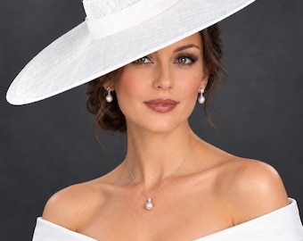 May include: A wide-brimmed white hat with a flat crown and a matching band. The hat is paired with a silver necklace featuring a single white pearl pendant and matching drop earrings, each with a small white pearl and a clear stone setting.