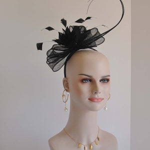 May include: Black feather and tulle headband with a large bow. The headband is worn on a white mannequin head.