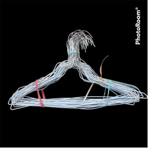 May include: A unique wire clothes hanger, crafted from numerous strands of silver-colored wire. The hanger is secured with red, green, and tan rubber bands. The design is simple, yet the multiple wires give it a textured appearance. The background is solid black.