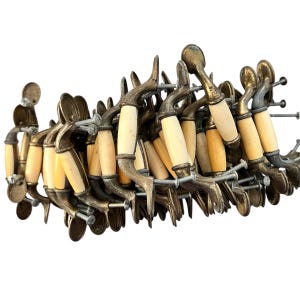 May include: A collection of vintage brass door handles with cream-colored, cylindrical grips. The handles are arranged in a circular pattern, showcasing their ornate design and aged appearance. Each handle is attached with screws.