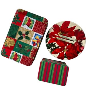 May include: Three decorative Christmas tins. One rectangular tin with a patchwork design of holly, poinsettias, and ornaments. A round tin with poinsettia flowers. A small rectangular tin with red and green stripes.
