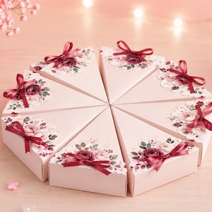 May include: Eight triangular light pink favor boxes arranged in a circular cake shape. Each box features a floral print with dark red roses, green leaves, and a small dark red satin ribbon bow attached to the top edge of the box lid.