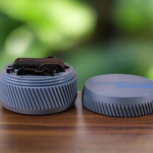 Pu&ograve; includere: Un contenitore di plastica grigio con un fermo nero. Il contenitore &egrave; aperto e il fermo &egrave; visibile. Il contenitore ha una superficie testurizzata e le parole "REMARKABLE" sono stampate sul coperchio.