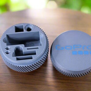 Pu&ograve; includere: Una scatola di contenimento in plastica grigia con scomparti per piccoli oggetti. La scatola ha un logo GoPro sul coperchio.