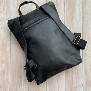 May include: A black leather backpack with a zippered pocket on the front and adjustable straps.