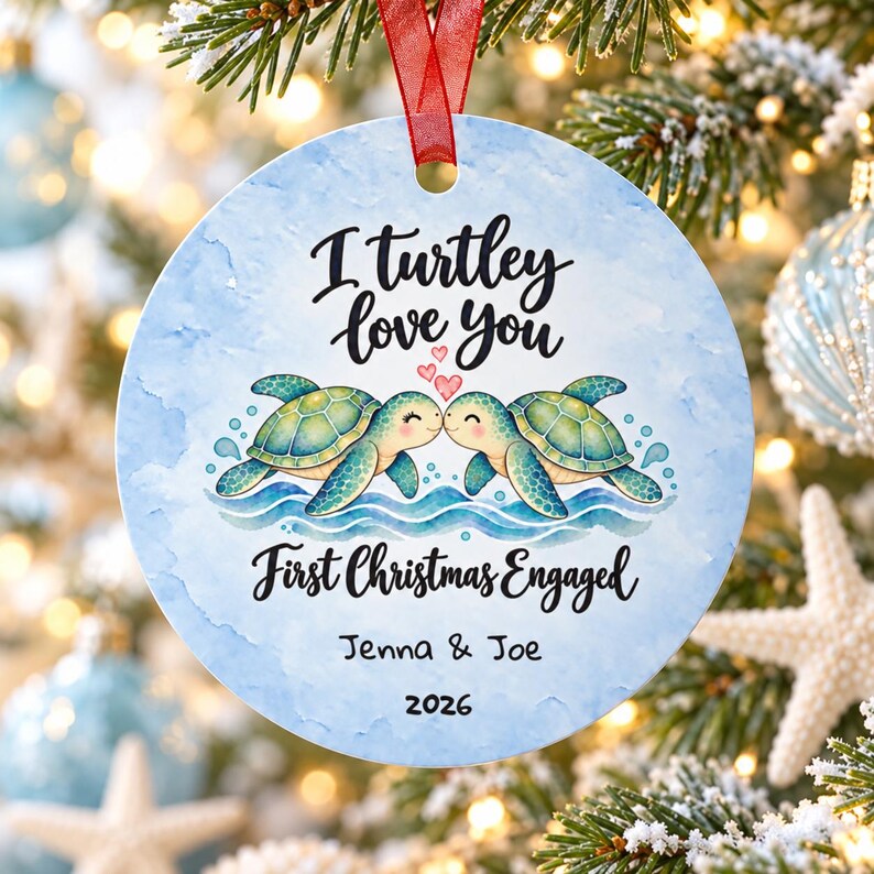 May include: A round ceramic Christmas ornament with a light blue watercolour background. It features two green sea turtles facing each other with three small red hearts above them. Text reads: I turtley love you, First Christmas Engaged, Jenna & Joe, 2026.