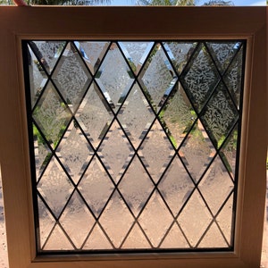 May include: A wood framed window with diamond shaped glass panes. The glass has a frosted texture.