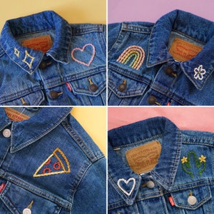 Puede incluir: Cuatro chaquetas vaqueras con diferentes dise&ntilde;os bordados. Los dise&ntilde;os incluyen un coraz&oacute;n, un arco&iacute;ris, una rebanada de pizza y un cactus con flores. Cada chaqueta tiene una etiqueta de Levi Strauss & Co.