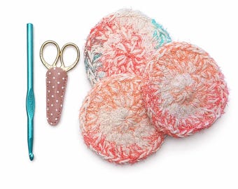 Peut inclure: Ensemble d'articles de crochet faits à la main, comprenant trois éponges rondes pour le visage aux tons de rouge, orange et blanc. Un crochet bleu turquoise et des ciseaux dorés avec un étui à pois sont également présents.