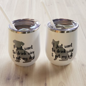 May include: Two white insulated wine tumblers with lids and straws. One features a dog silhouette and the text "I just want to drink wine & pet my dog." The other has a cat silhouette and the text "I just want to drink wine & pet my cat."