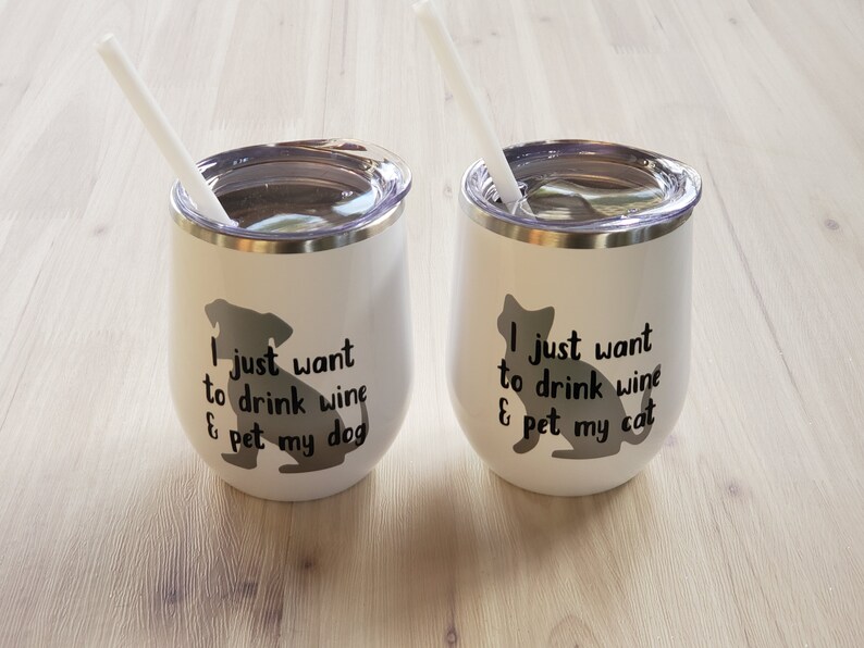 May include: Two white insulated wine tumblers with lids and straws. One features a dog silhouette and the text "I just want to drink wine & pet my dog." The other has a cat silhouette and the text "I just want to drink wine & pet my cat."