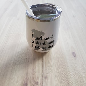 May include: White insulated wine tumbler with a clear lid and a white straw. The tumbler features a gray silhouette of a dog and the text "I just want to drink wine & pet my dog" in black. The tumbler is designed for cold beverages.