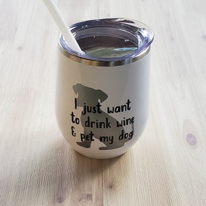 May include: White insulated wine tumbler with a clear lid and a white straw. The tumbler features a black silhouette of a dog and the text "I just want to drink wine & pet my dog."