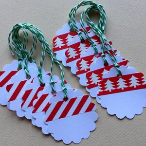 May include: A set of eight white gift tags with scalloped edges. The tags are decorated with red and white candy cane stripes and red and white Christmas trees. Each tag has a hole punched at the top and is attached to a green and white twine.