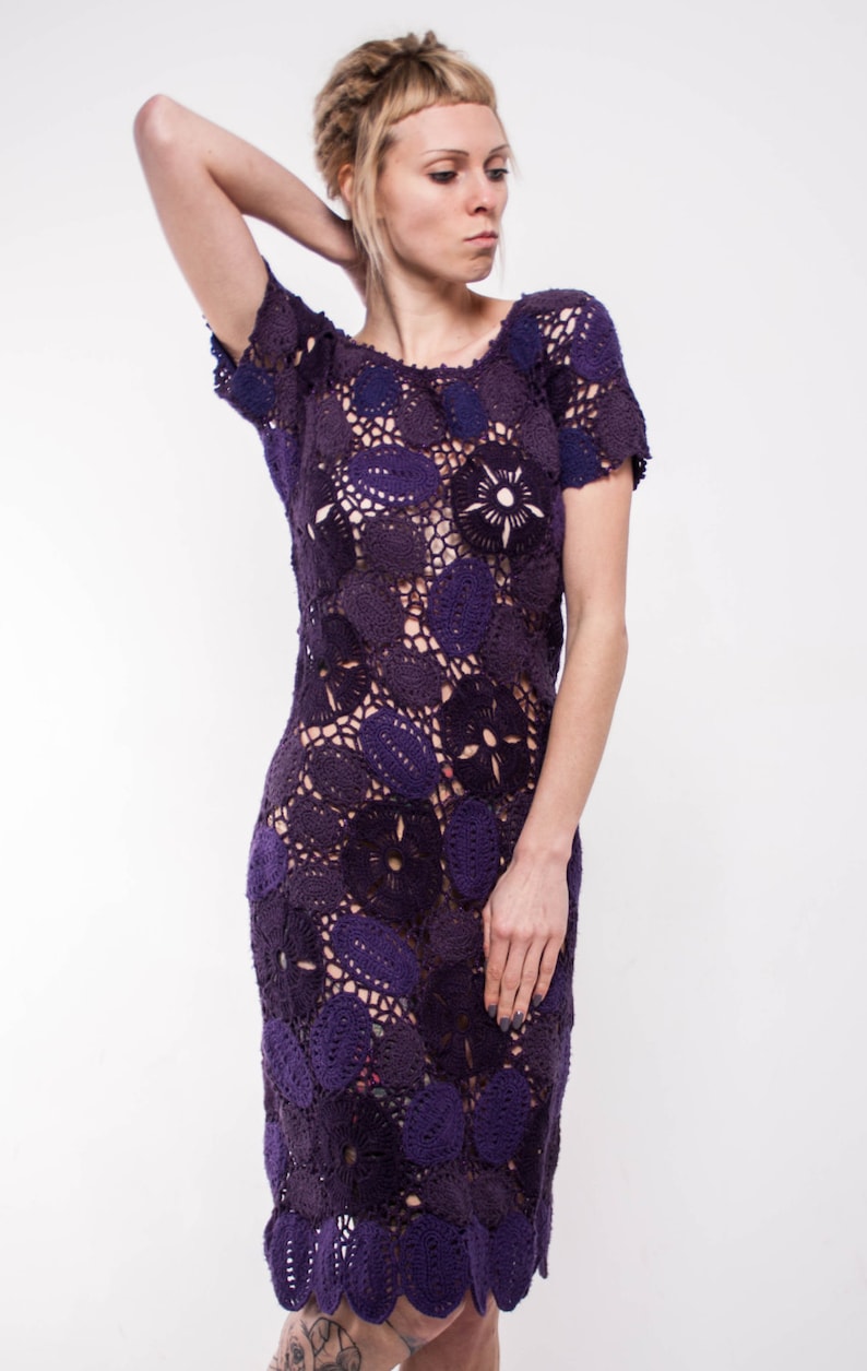 May include: A purple crochet dress with a floral pattern. The dress is sleeveless and has a loose fit.