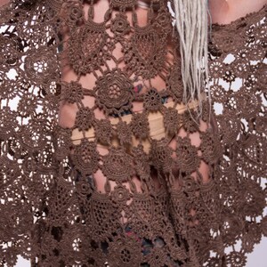 May include: A brown crochet dress with a delicate floral pattern. The dress is sheer and has a loose, flowing fit.