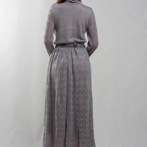 May include: A gray knitted dress with a chevron pattern. The dress has a turtleneck and long sleeves. The model is wearing black heels.