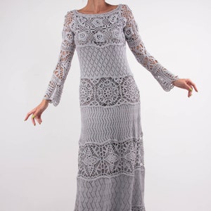 May include: A long, gray crochet dress with a floral design. The dress has a loose fit and long sleeves.