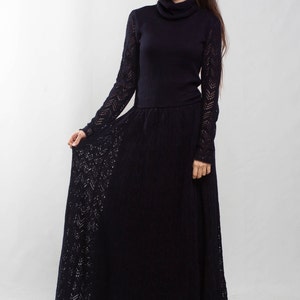 K&ouml;nnte beinhalten: Ein langes schwarzes Strickkleid mit Rollkragen und einem spitzem Muster. Das Kleid ist am Oberk&ouml;rper figurbetont und geht in einen weiten Rock &uuml;ber.